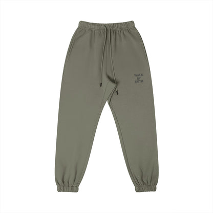 Omina Studio olive green cotton sweatpants with 'Walk By Faith' graphic, elastic waistband, and tapered fit.