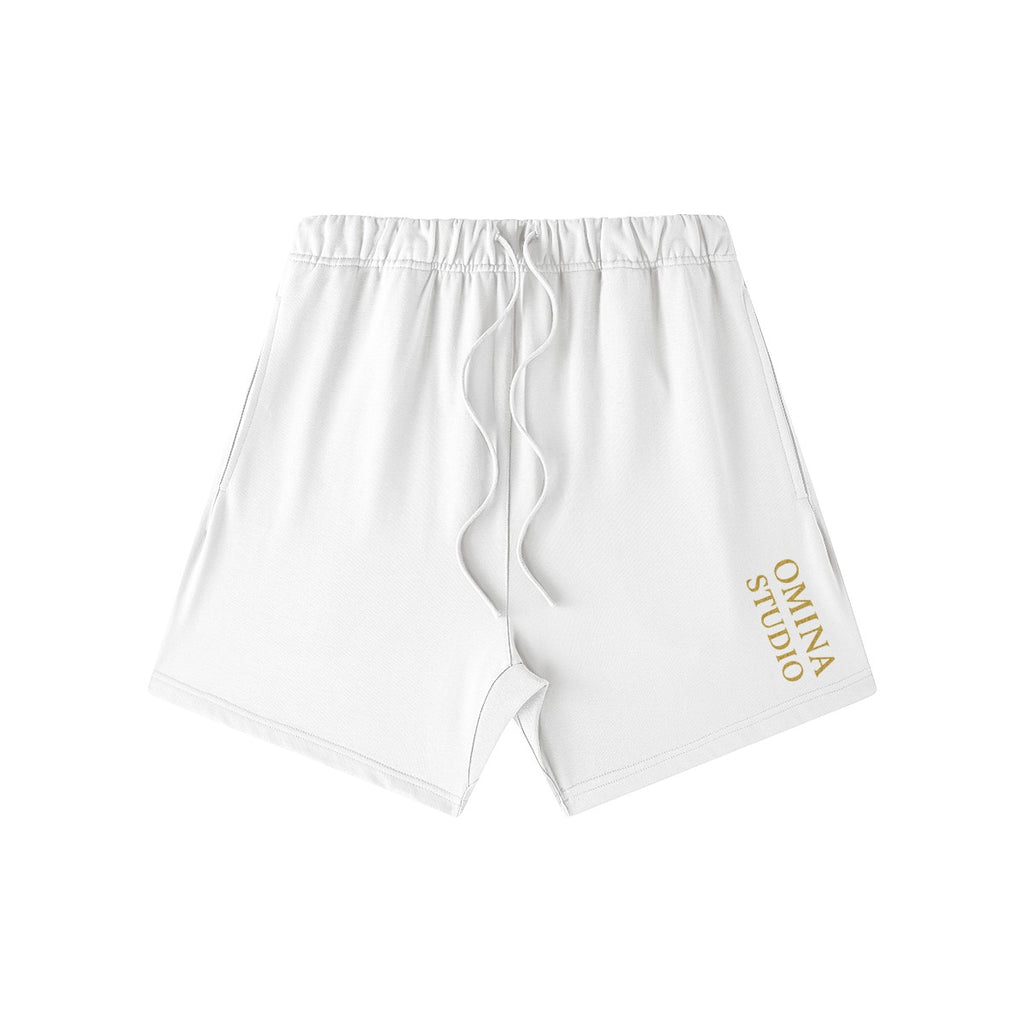 Omina Studio white heavyweight cotton French terry shorts with drawstring and gold logo detail.