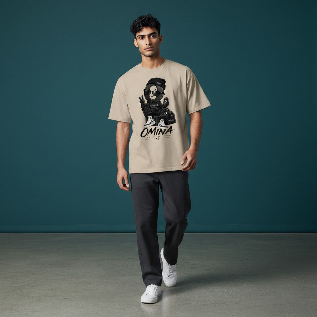 Model wearing an Omina O Urban beige cotton t-shirt with a graphic print, styled with dark trousers and white sneakers.