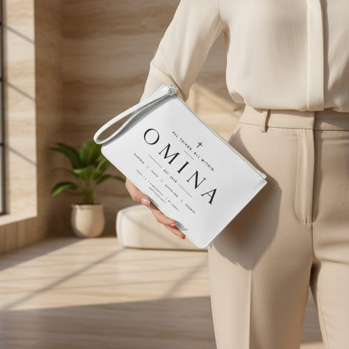Omina white saffiano faux leather wristlet clutch with typographic design and cross, held by a woman in beige.