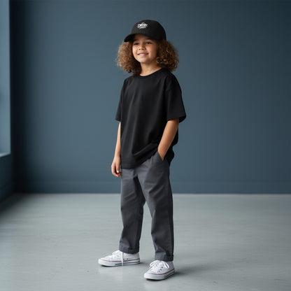 Omina Youth black cotton twill low-profile cap with white graffiti-style logo and adjustable buckle closure.