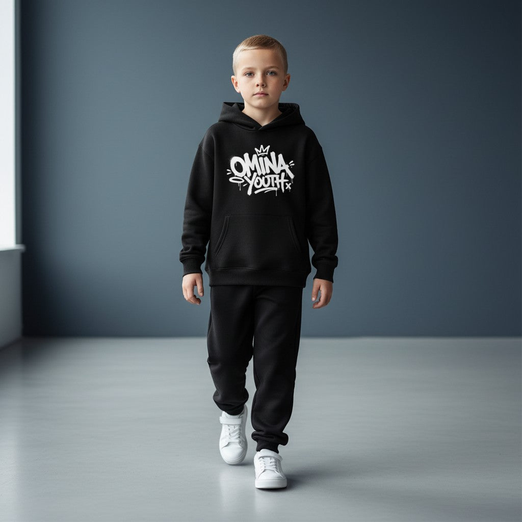 Young boy wearing an Omina black fleece pullover hoodie with white graffiti-style chest graphic and matching joggers.