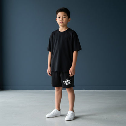 Omina Youth black relaxed fit shorts with white graffiti-style logo on the left leg. Elastic waistband.