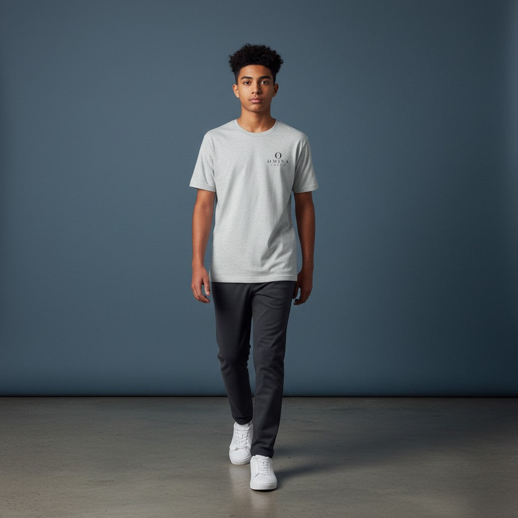 A young man wearing an Omina grey performance tee with a small logo on the chest, paired with dark trousers.