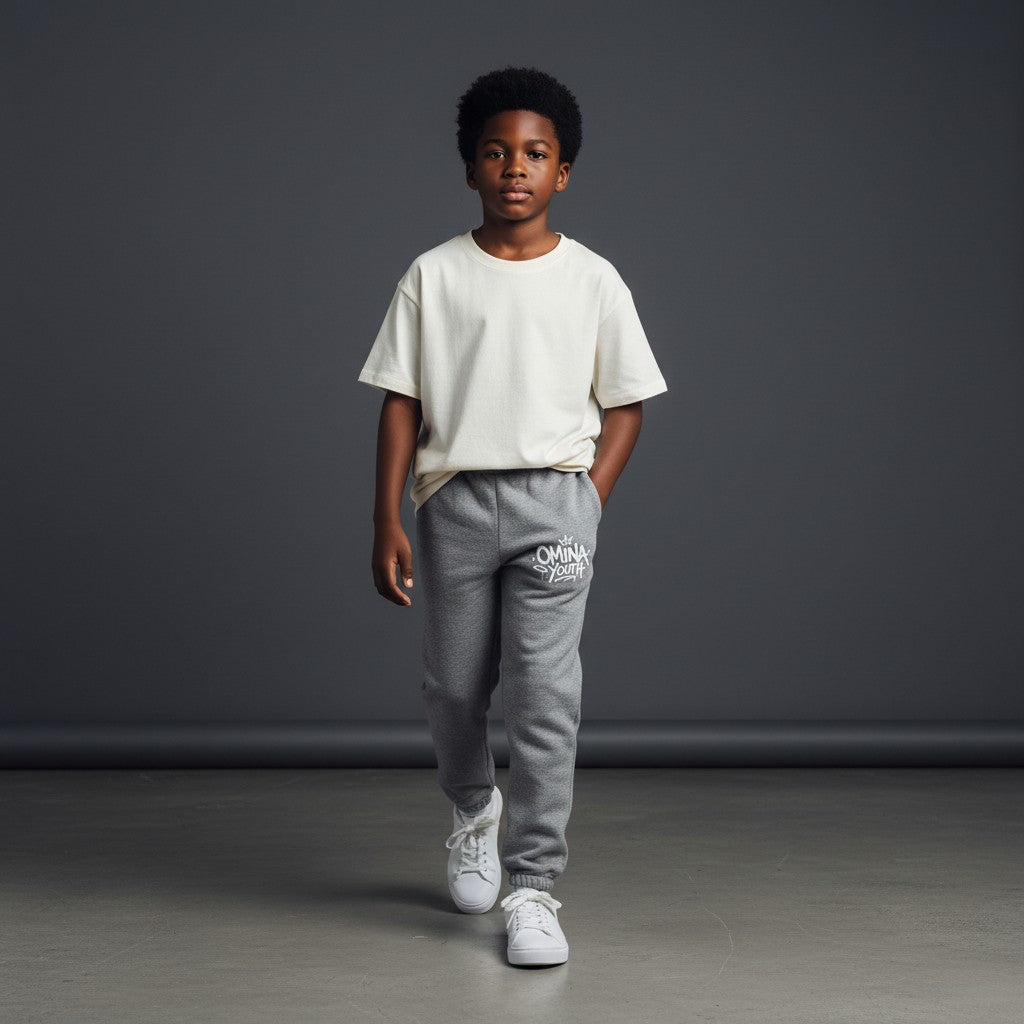 Omina Youth grey sweatpants with relaxed fit and white graffiti-style logo on left thigh.