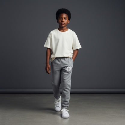 Omina Youth grey sweatpants with relaxed fit and white graffiti-style logo on left thigh.
