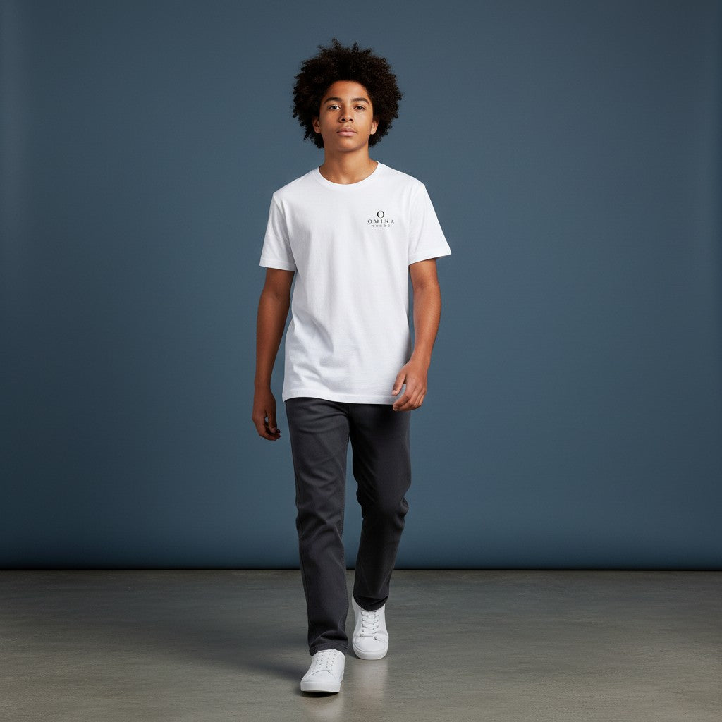 A boy wearing an Omina white moisture-wicking performance t-shirt with a small logo, paired with dark grey trousers.